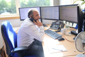 image00075 A male member of office staff, smiling whilst taking a phone call at his desk